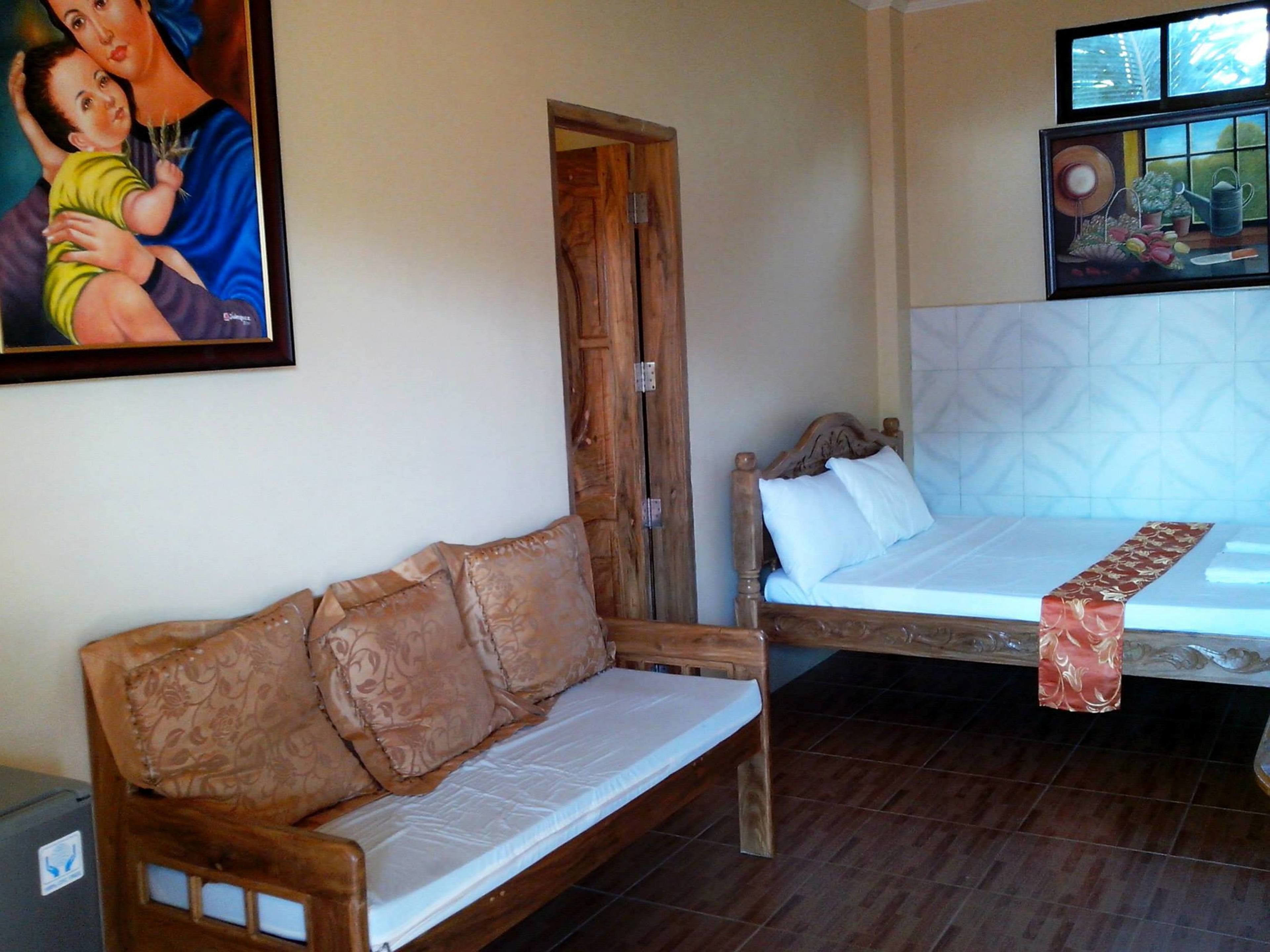 A bedroom with a wooden bed, a wooden sofa, and a painting on the wall.