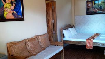 A bedroom with a wooden bed, a wooden sofa, and a painting on the wall.