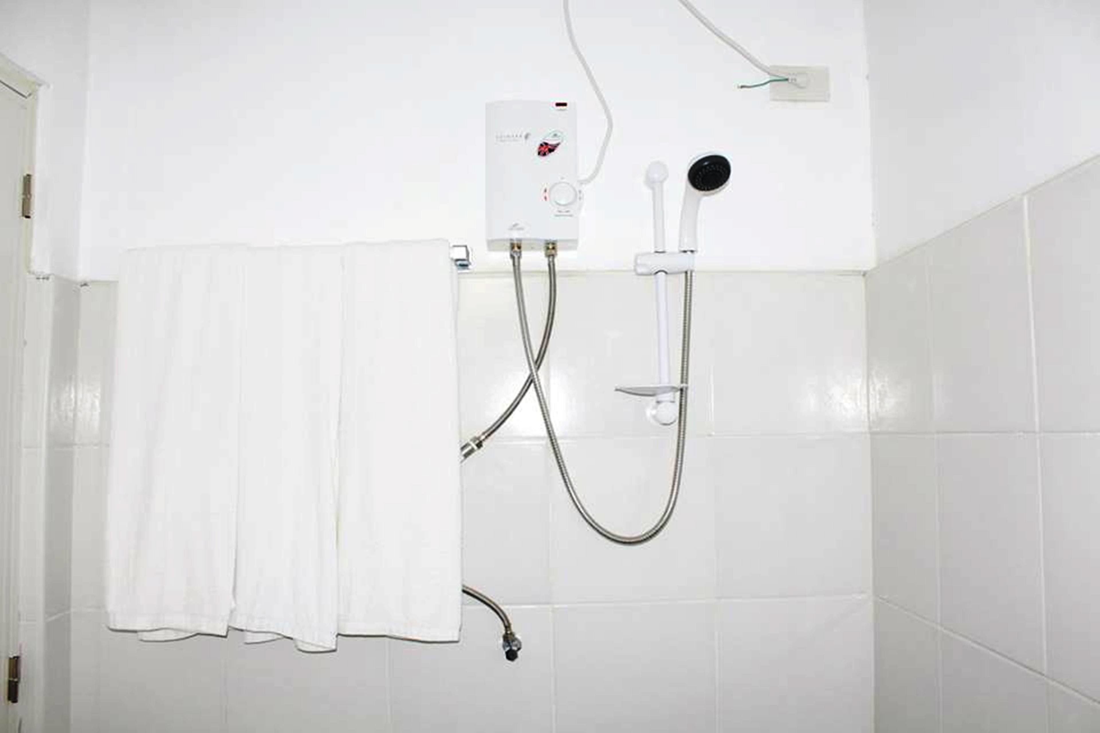 A bathroom with a white shower, a towel hanging on the wall, and a white tiled floor.