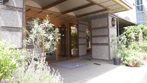 L’entrée d’un hôtel, dotée d’un porche, de murs en pierre et de plantes en pot.