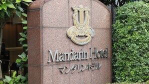 Une plaque en pierre portant l’inscription « Mandarin Hotel » et surmontée d’un blason.