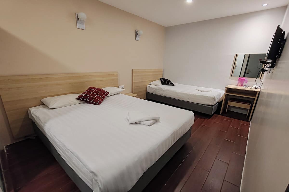 A hotel room with two beds, a small desk, a mirror, and a TV mounted on the wall.