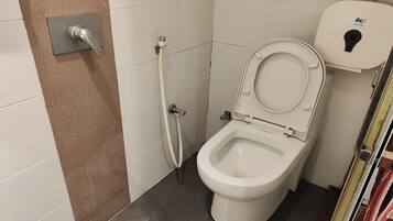 Un baño con inodoro, ducha y toallero.