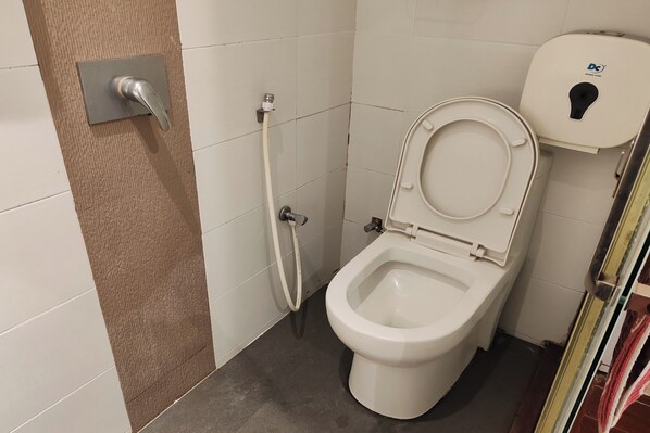 Un baño con inodoro, ducha y toallero.