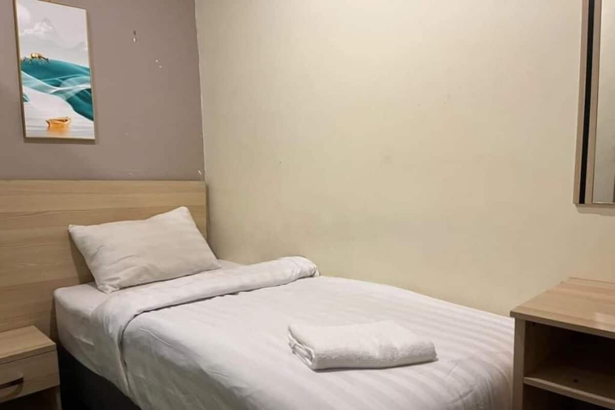 A neatly made bed with white bedding, a wooden headboard, a bedside table, and a wall-mounted picture.