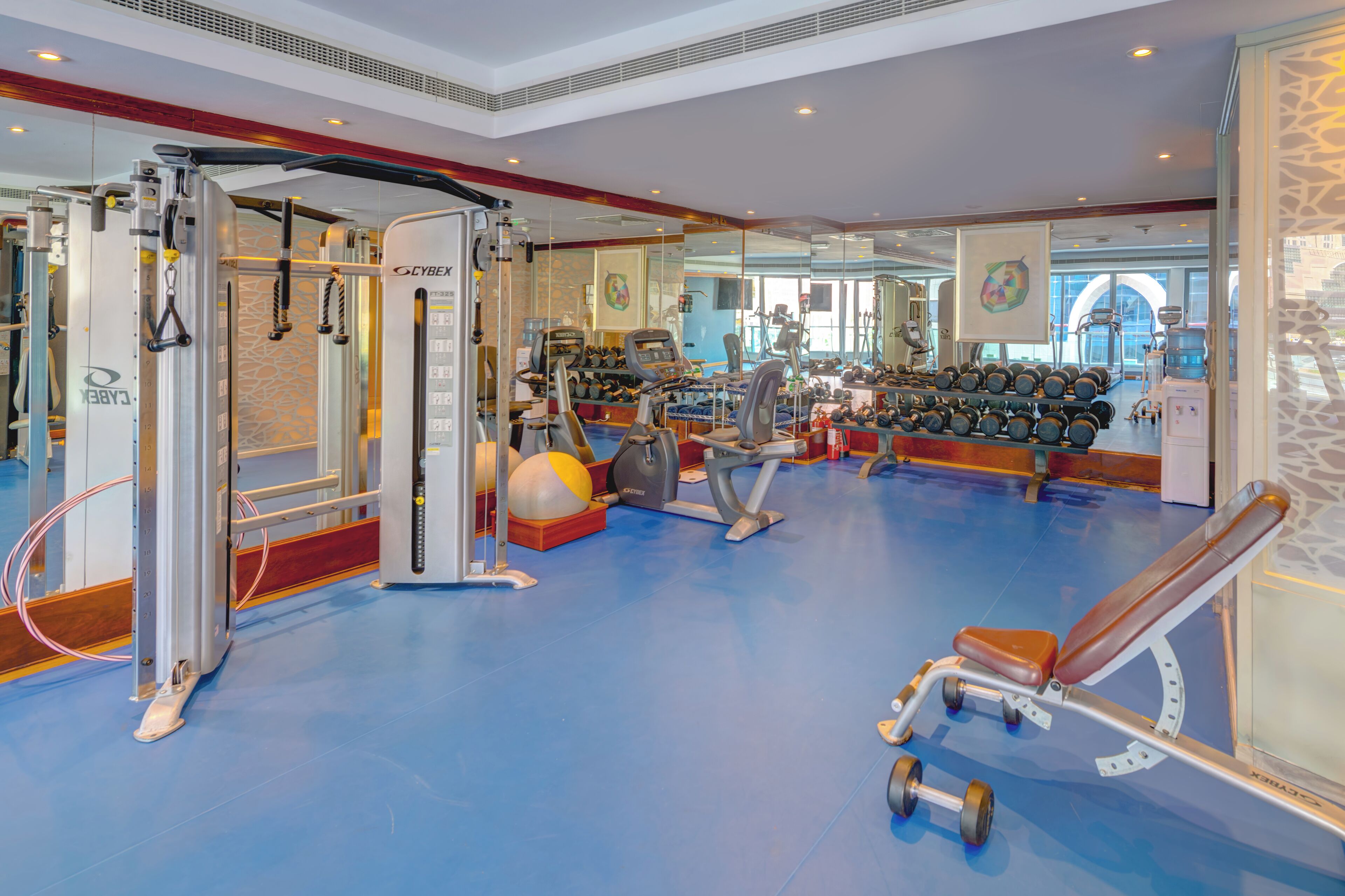 Une salle de sport équipée de matériel d’exercice, d’un rameur et d’un banc.