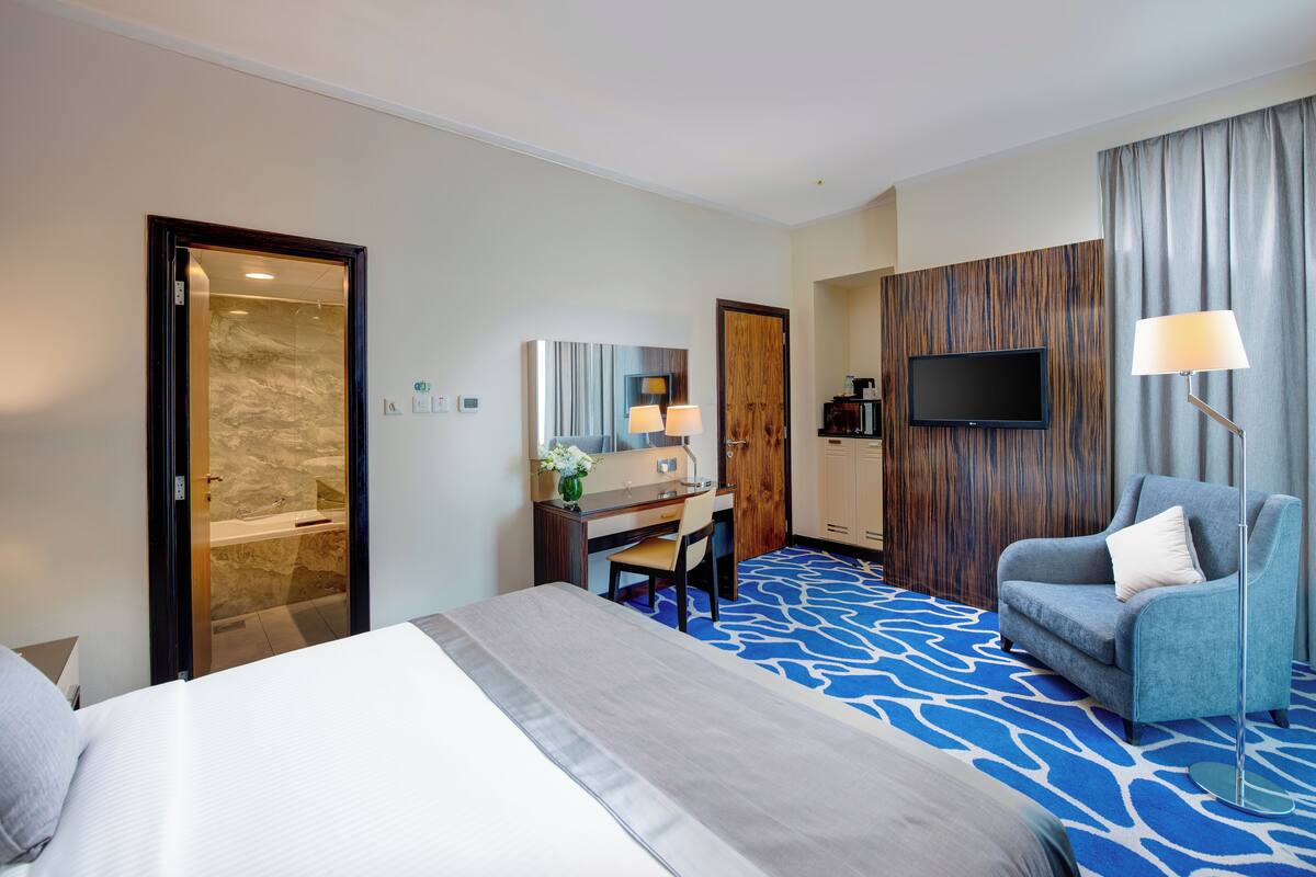 Une chambre d’hôtel comprenant un lit, un bureau, une chaise, une télévision et une salle de bain.