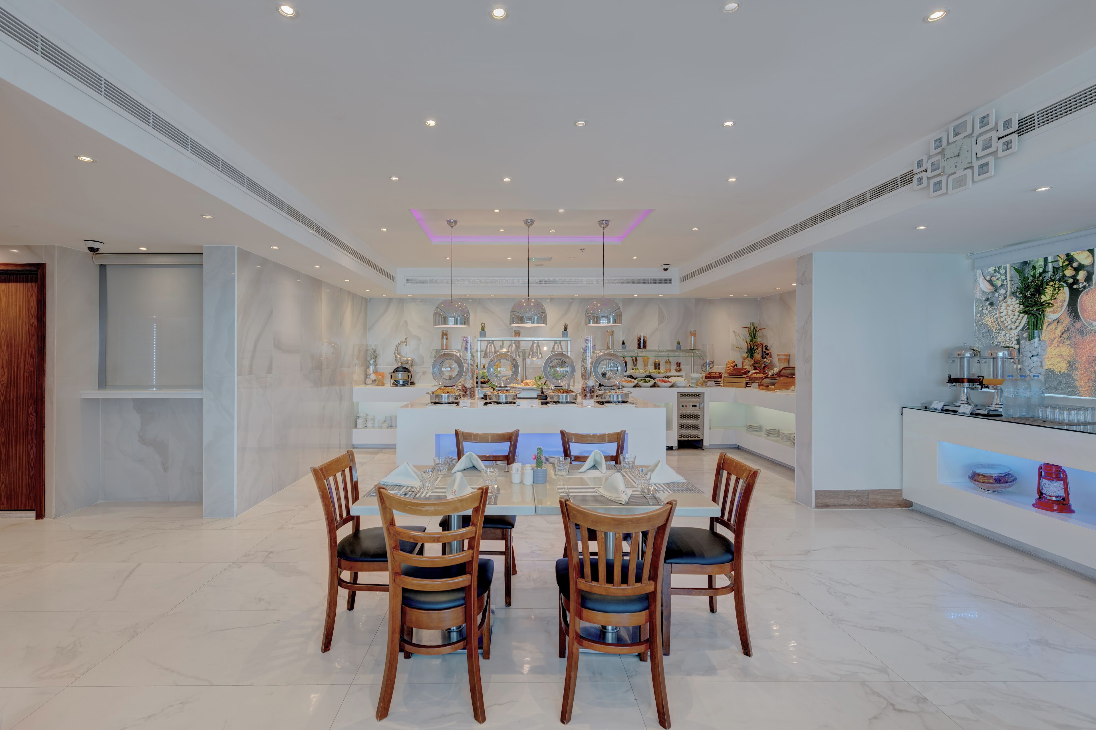 Un comedor amplio con piso de mármol, sillas de madera y una isla central con una mesita de vidrio.