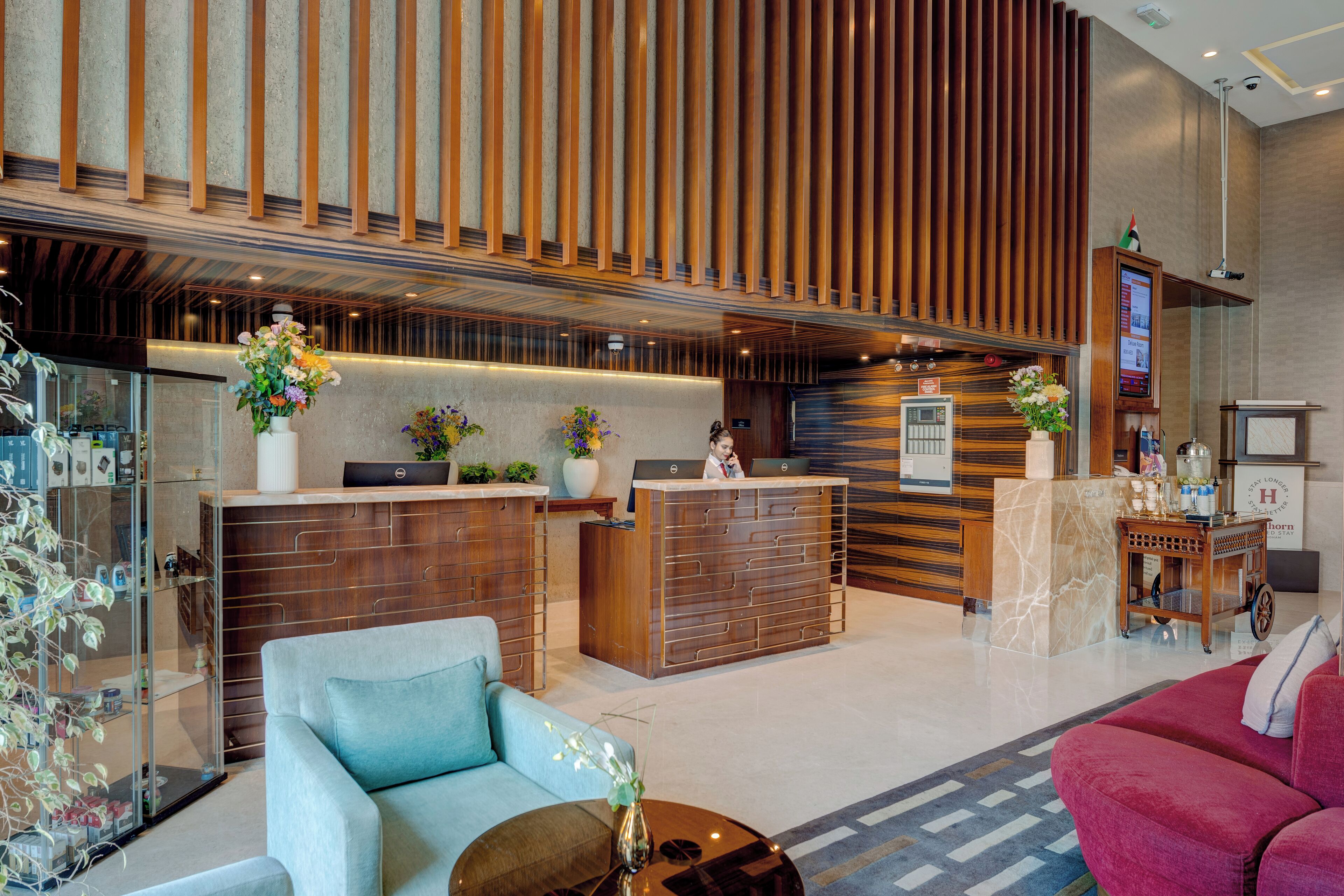Un moderno vestíbulo de hotel con mostrador de recepción, zona de estar y una planta decorativa.