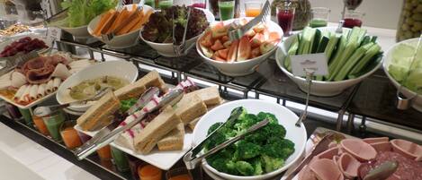 A buffet with various food items including sandwiches, salads, and meats.