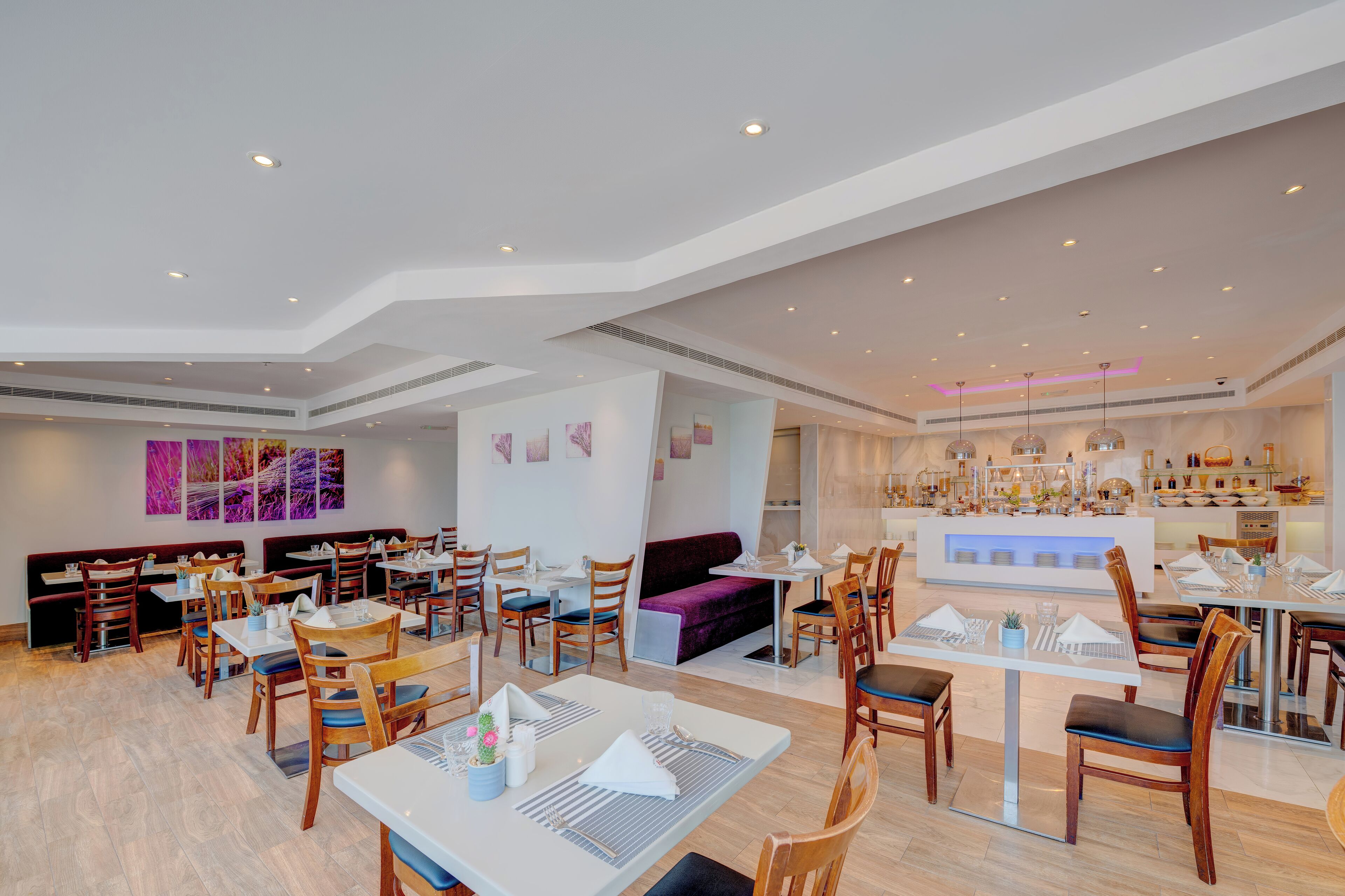 Un restaurante moderno con varias zonas de comedor, incluyendo cabinas y mesas, y una barra central.