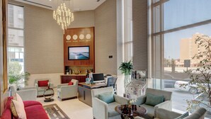 A spacious lobby with a large TV, comfortable seating, a reception desk, and a view of the street. - Hawthorn Suites by Wyndham Abu Dhabi City Centre (Abu Dhabi)