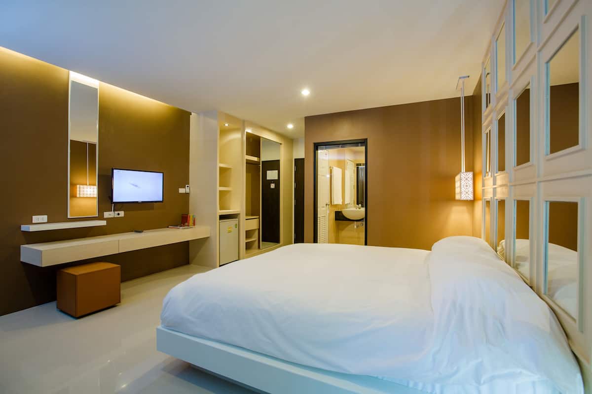 Una habitación de hotel moderna con una cama grande, televisión, tocador con espejo y vestidor.