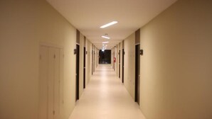 A long, narrow hallway with doors on both sides, leading to individual rooms. - Naka Residence (Wichit)