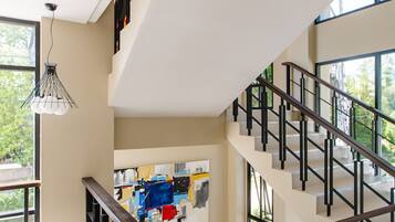 A modern interior with a staircase, a dining area with chairs, and a large window providing natural light.