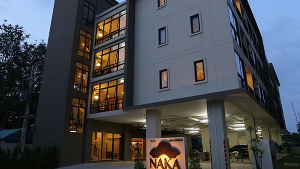 A modern hotel building with multiple floors and a well-lit entrance. - Naka Residence (Wichit)