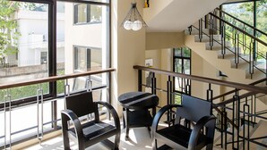 A modern interior with a staircase, two black chairs, and a hanging light fixture. - Naka Residence (Wichit)
