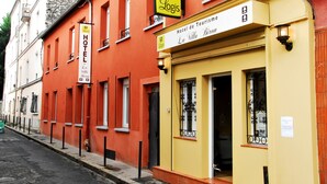 Un hôtel appelé « Hotel de Tourisme La Villa Bion », avec une façade jaune et un bâtiment rouge attenant.
