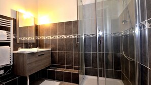 Une salle de bain moderne avec une douche à parois de verre, un meuble-lavabo en bois et un porte-serviettes.