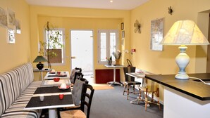 Un coin repas comprenant un canapé à rayures, une table avec des chaises, une lampe et une vue sur l’extérieur.