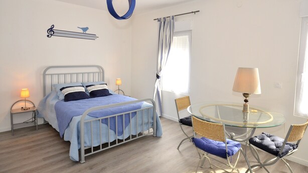 Une chambre à coucher comprenant un lit, une table de chevet, une lampe et une table ronde en verre, ainsi que des chaises.