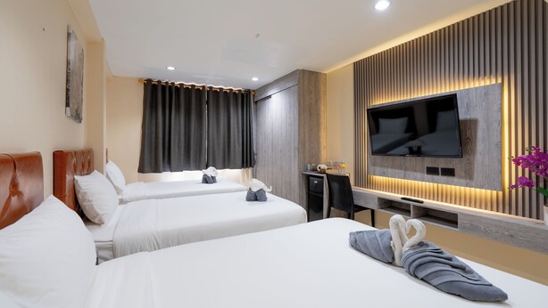 A hotel room with two beds, a desk, a flat-screen TV, and a wall-mounted TV. - Square One Hotel Patong (Patong)