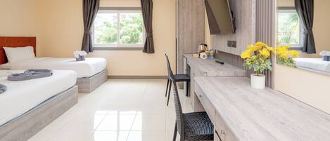 A hotel room with two beds, a desk, a chair, a TV, and a window with curtains.