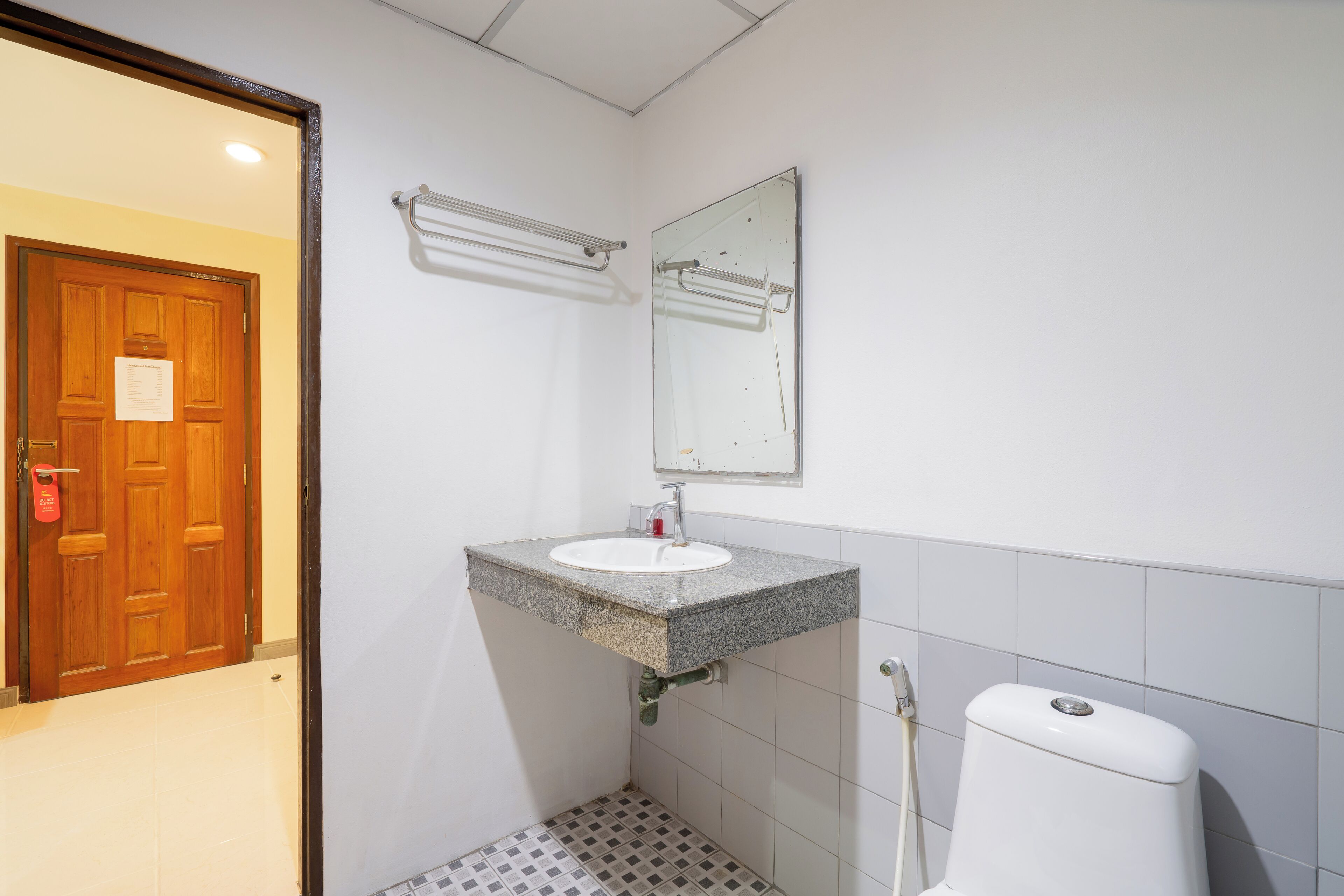 A bathroom with a wooden door, a white sink, a mirror, and a toilet.
