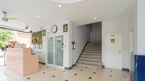 A reception area with a reception desk, a clock, a staircase, and a fire extinguisher. - Square One Hotel Patong (Patong)