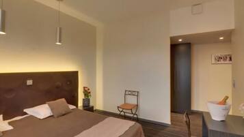 Una habitación de hotel moderna con una cama grande, un escritorio con una silla y una mesita con una botella.