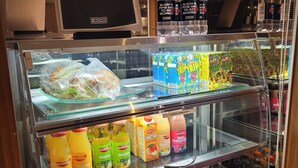 Een drankendisplay met diverse dranken en een menubord erboven.