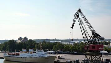 A large cargo ship docked at a port with cranes and industrial buildings in the background.
