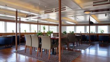 Un amplio comedor con suelo de madera, varias mesas y sillas.