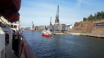 A river with a red boat and industrial structures in the background.