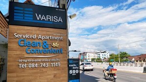 Un cartel para un complejo de apartamentos con servicios llamado 'WARISA', con un número de contacto y un número de atención al cliente.
