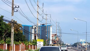 Vista de una calle con edificios, líneas eléctricas y vehículos.