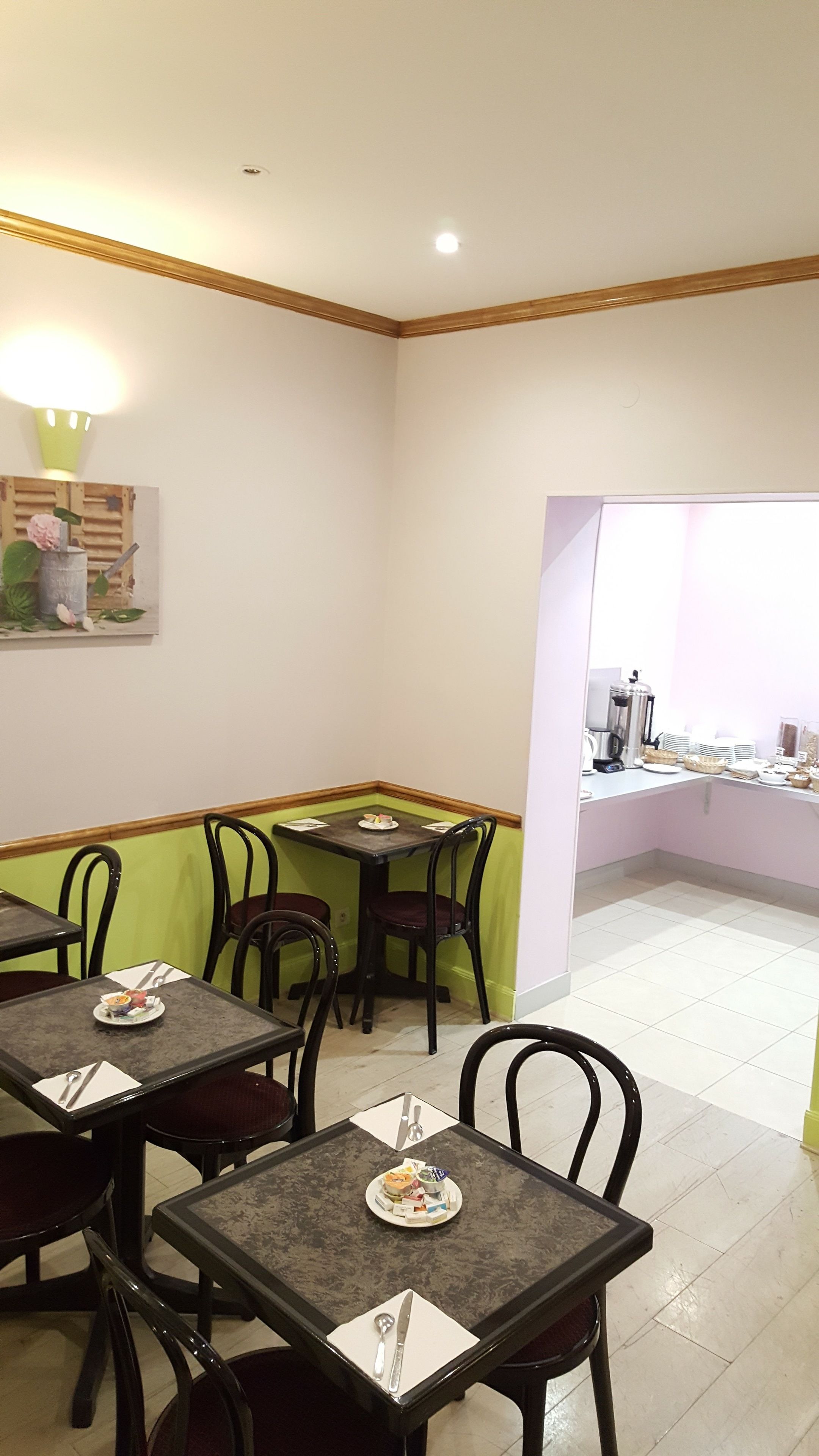 Un comedor con mesas y sillas, un cuadro en la pared y una ventana con vistas.