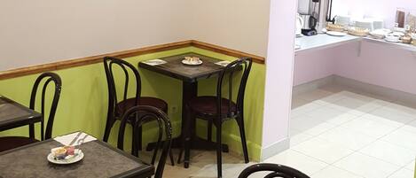 Un comedor con mesas y sillas, un cuadro en la pared y una ventana con vistas.
