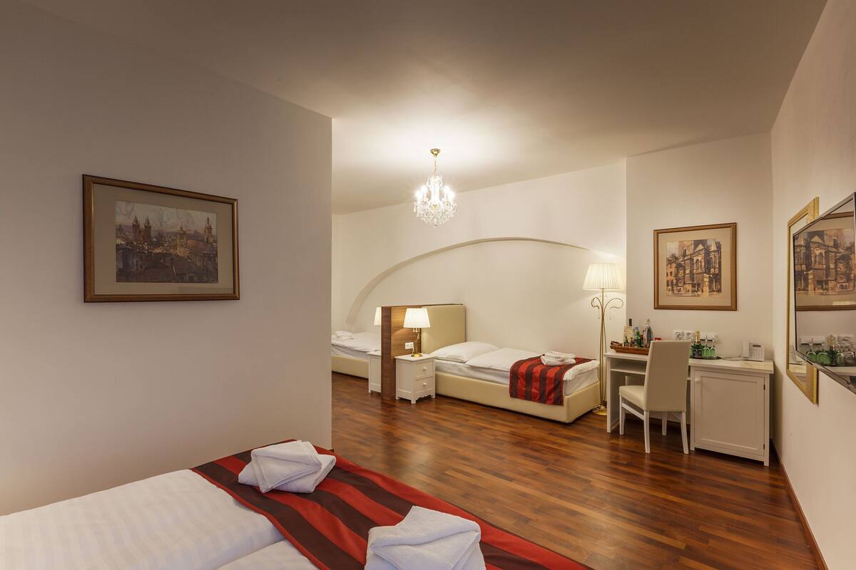 A hotel room with a bed, desk, chair, and a chandelier.