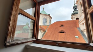 A window with a view of a building with a green dome and a tower. - Little King Hotel U Malvaze (Prague)