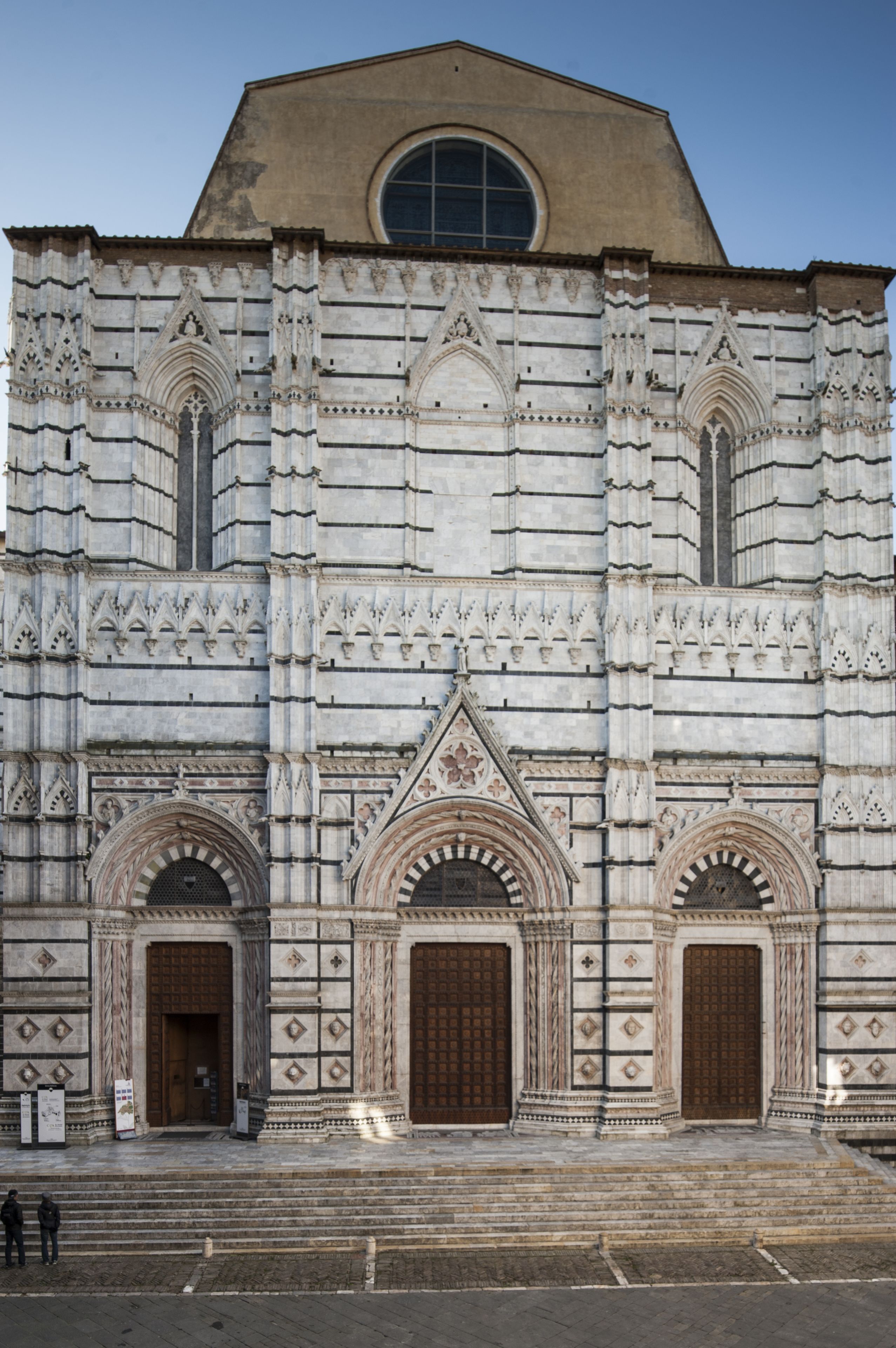 Un edificio histórico con elaboradas esculturas de piedra, grandes puertas de madera y un arco pronunciado.