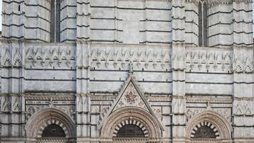 Un edificio histórico con elaboradas esculturas de piedra, grandes puertas de madera y un arco pronunciado.