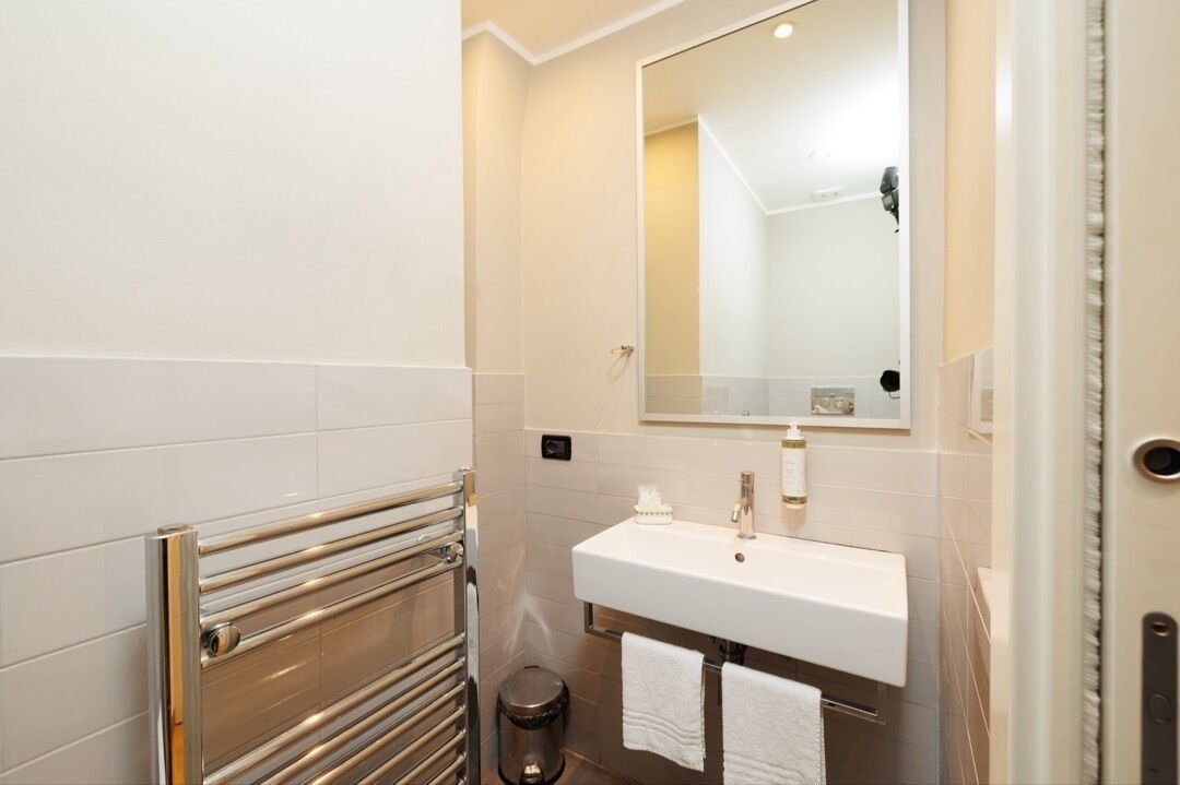 A bathroom with a white sink, a mirror, and a towel rack.