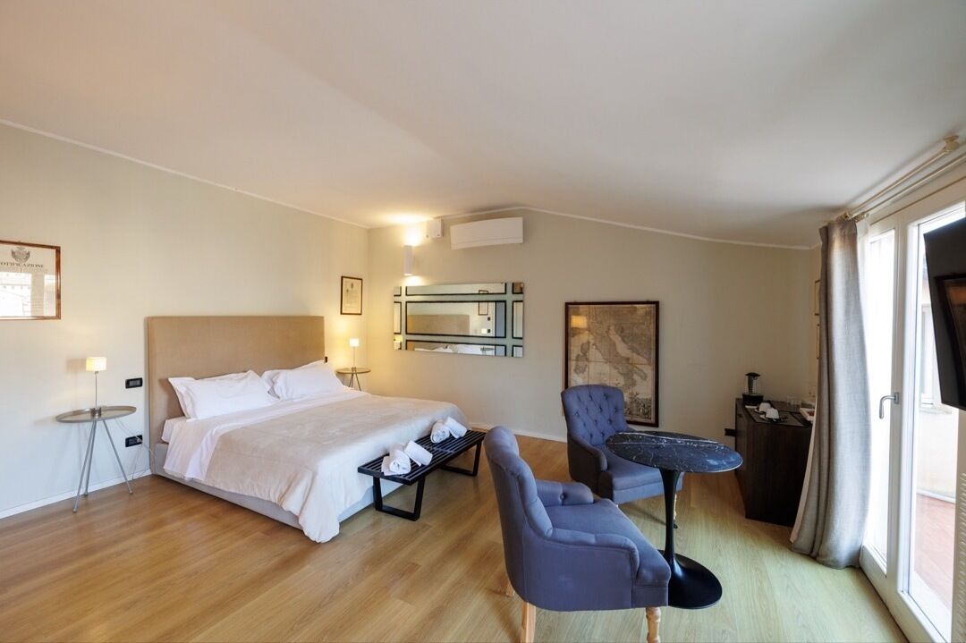 A hotel room with a bed, a chair, a small table, and a window.