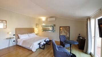 A hotel room with a bed, a chair, a small table, and a window.