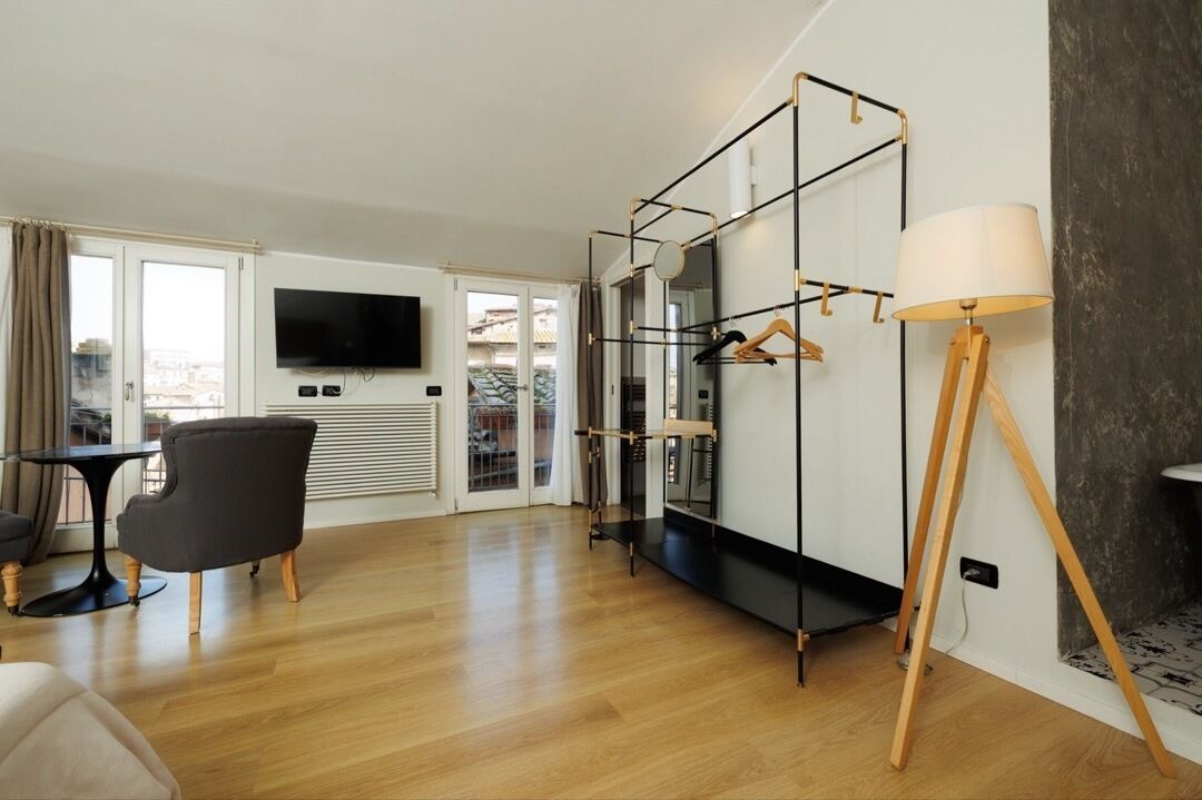 Un salón moderno con una televisión de pantalla plana, un sillón negro, suelo de madera y un espejo grande con marco de madera.