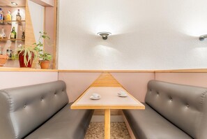 A corner booth with a wooden table and cushioned seating. - Hotel Montecarlo (Encamp)
