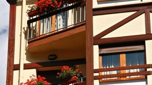 Un edificio de varios pisos con balcones, cada uno con barandillas de madera y jardineras con flores.