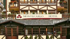 Un hotel de varios pisos con balcones decorados con flores, un restaurante y un letrero que dice "Montecarlo Hotel".