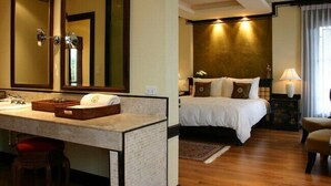 A hotel room with a large mirror, a bed with white linens, a nightstand with a lamp, and a wooden floor. - Bann Tazala Exclusive Residence (Chiang Mai)